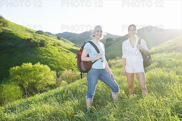 Caucasian mother and daughter smiling on grassy hillside