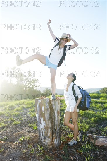 Woman watching friend balancing on dilapidated stump