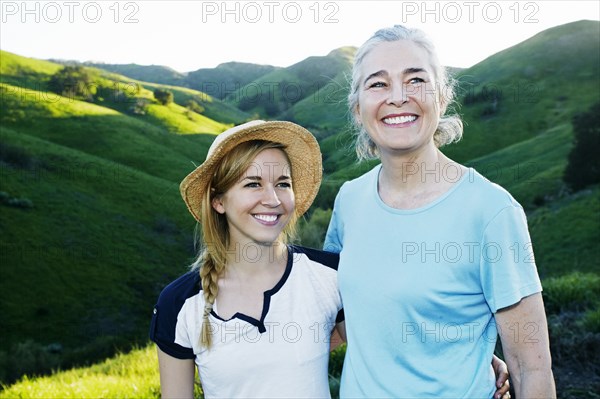 Caucasian mother and daughter smiling on rural hilltop