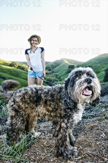 Caucasian woman walking dog on rural hilltop