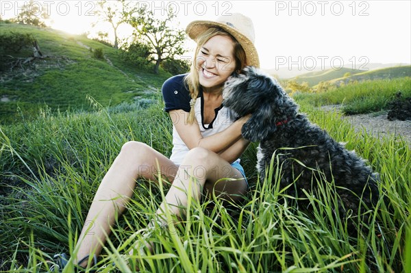 Caucasian woman petting dog in field
