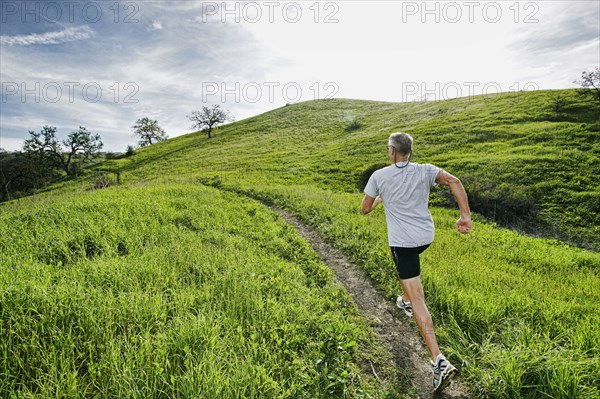 Older Caucasian man jogging on dirt path