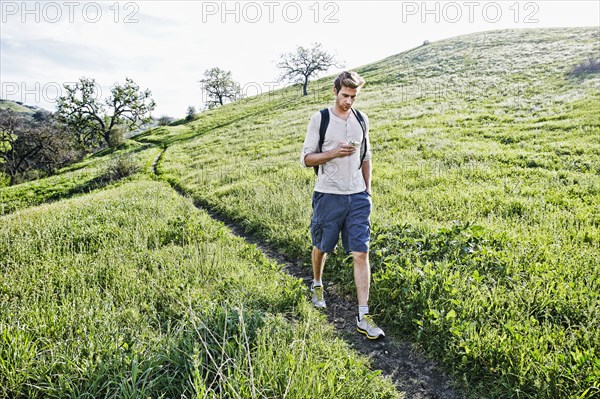 Caucasian man using cell phone on dirt path