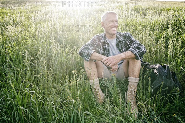 Older Caucasian man sitting on grassy hillside