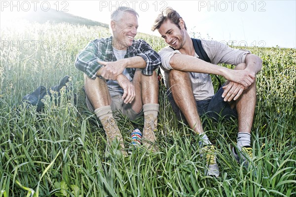 Caucasian father and son sitting on grassy hillside