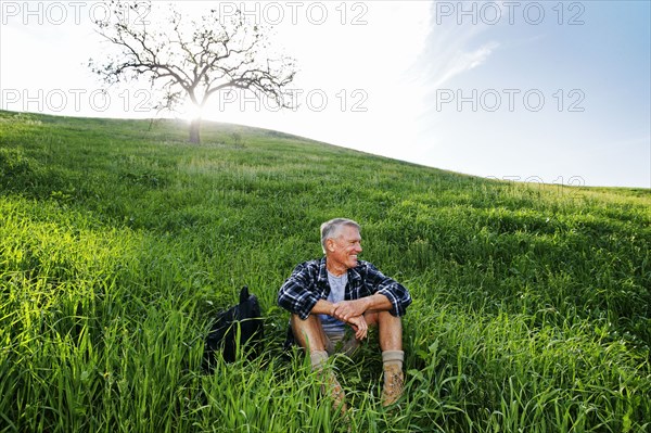 Older Caucasian man sitting on grassy hillside