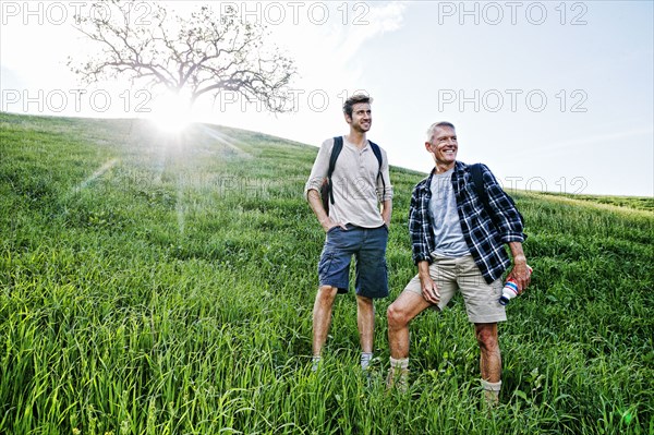 Caucasian father and son standing on grassy hillside