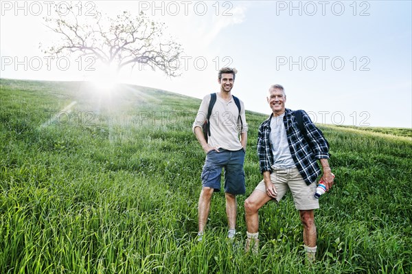 Caucasian father and son standing on grassy hillside