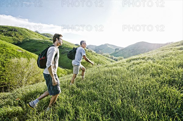 Caucasian father and son walking on grassy hillside