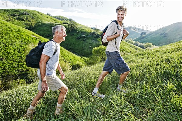 Caucasian father and son walking on grassy hillside