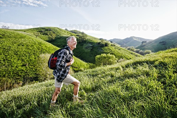 Older Caucasian man walking on grassy hillside