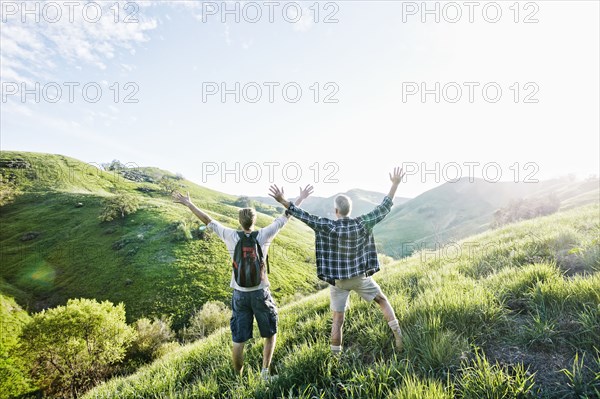 Caucasian father and son cheering on grassy hillside