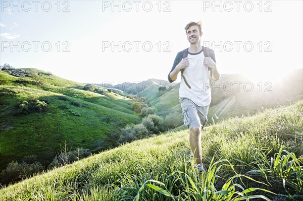Caucasian man walking on rural hillside