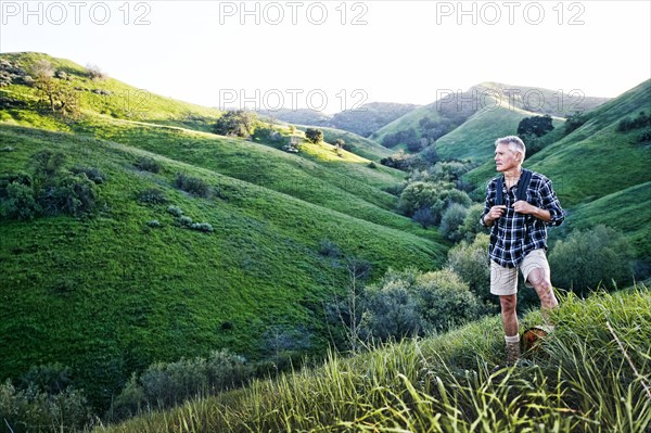 Older Caucasian man smiling on grassy hillside