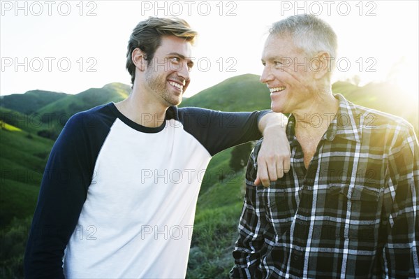 Caucasian father and son smiling on rural hilltop