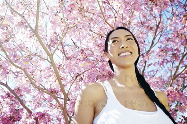 Mixed race woman standing under flowering tree