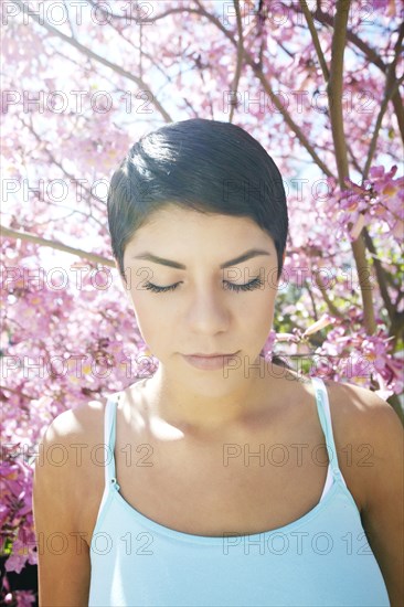 Hispanic woman standing under flowering tree