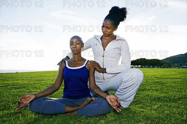 Woman practicing yoga with teacher in park