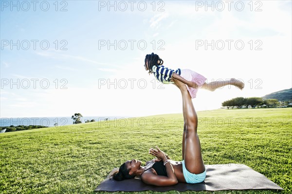 Mother holding daughter with legs in park