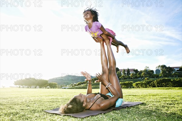 Mother holding daughter with legs in park