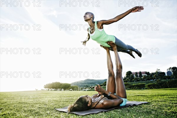Woman and friend practicing acro yoga in park