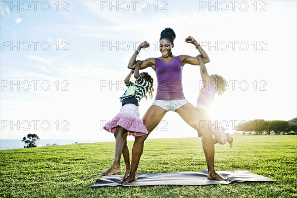 Woman lifting children with biceps in park