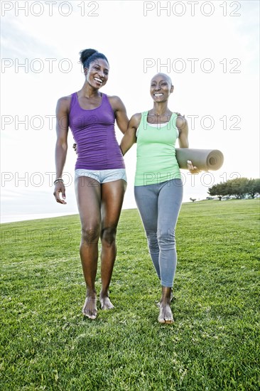 Women carrying yoga mat in park