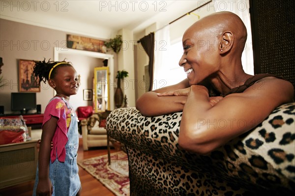 Black mother and daughter smiling in living room