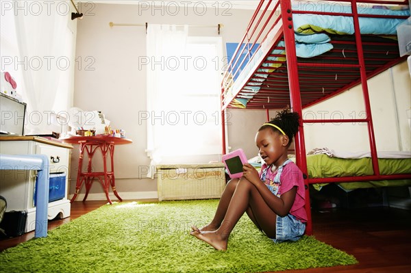 Black girl using digital tablet in bedroom