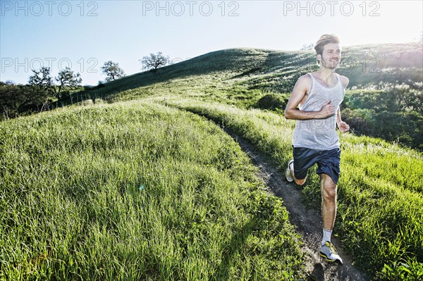 Caucasian athlete running on rural trail