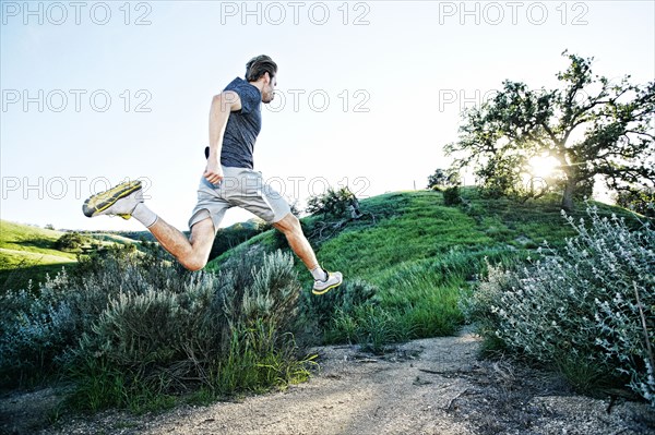 Caucasian athlete running on rural trail