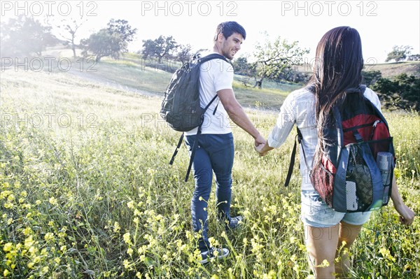 Couple carrying backpacks in field