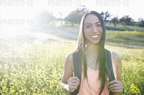 Mixed race woman carrying backpack in field