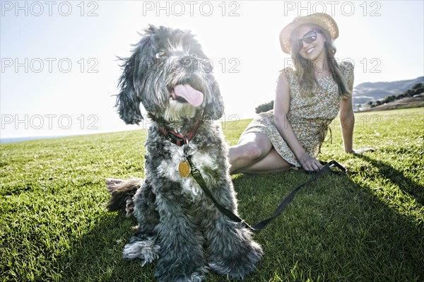 Caucasian woman sitting in field with dog