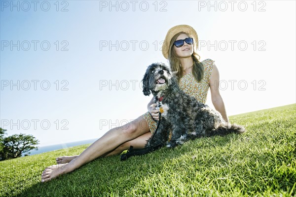 Caucasian woman sitting in field with dog