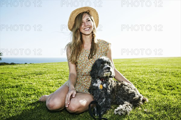 Caucasian woman sitting in field with dog
