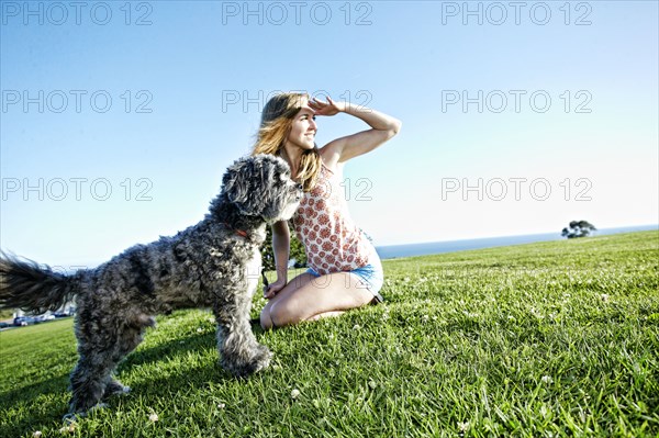 Caucasian woman sitting in field with dog