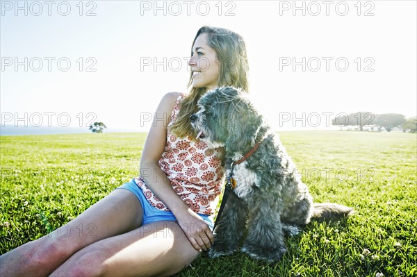 Caucasian woman sitting in field with dog