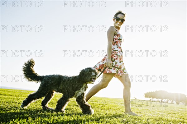 Caucasian woman walking dog in field