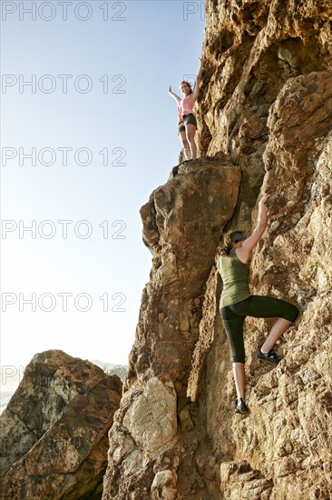 Women climbing rock formation