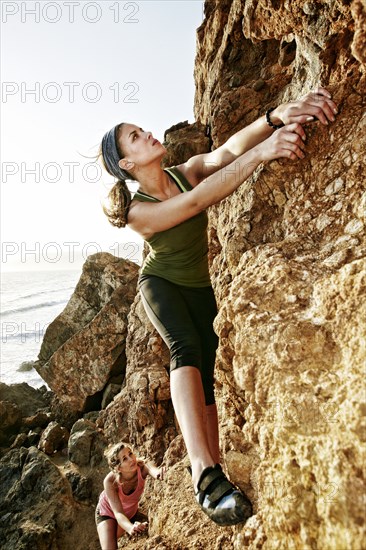 Women climbing rock formation