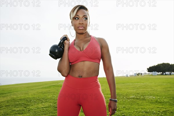 Black woman lifting weights in field