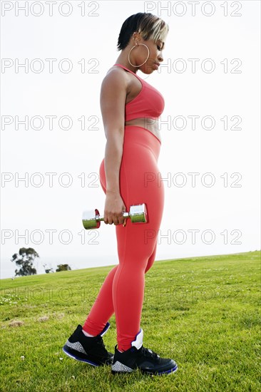 Black woman lifting weights in field