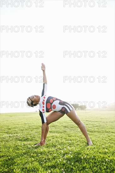 Black woman practicing yoga in field