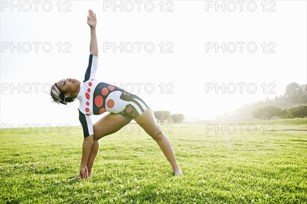 Black woman practicing yoga in field