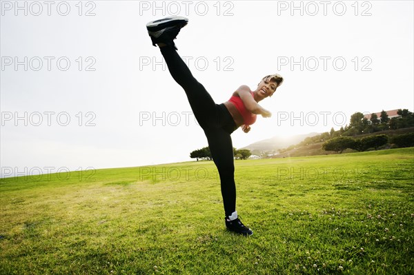 Black woman kick boxing in field