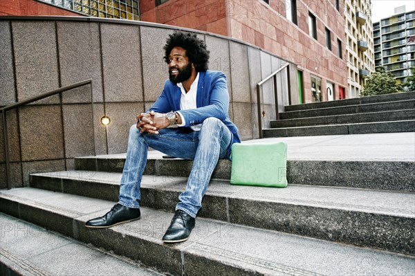 Mixed race businessman sitting on steps