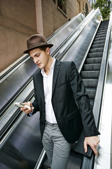 Caucasian businessman using cell phone on escalator