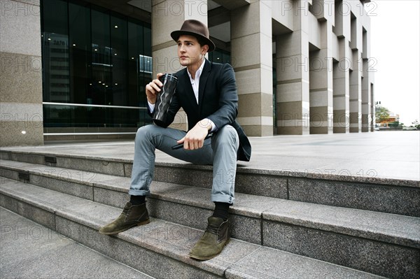 Caucasian businessman drinking coffee on steps