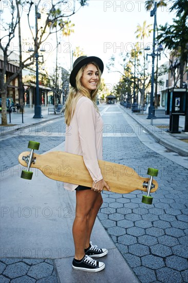 Caucasian woman carrying skateboard